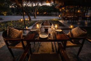 a wooden table with plates and candles on it at Badi Meadows By Wilkisto Near Fatehsagar Lake in Udaipur