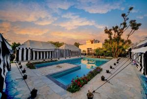 a resort swimming pool with a sunset in the background at Badi Meadows By Wilkisto Near Fatehsagar Lake in Udaipur