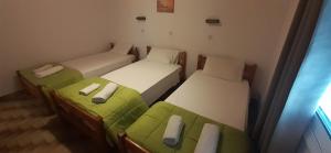 three beds in a room with green and white at Apartments Elena in Kavos