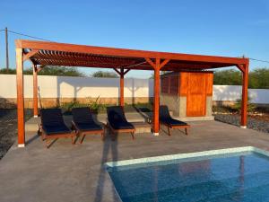 a patio with chairs and a pavilion next to a pool at Magnifique villa avec piscine privée à 300m de la plage in Vila do Porto