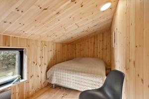 a small bedroom in a wooden cabin with a bed at LK2209-Lokken-Soltoften-50 in Nørre Lyngby