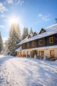 a house in the snow with the sun behind it at Penzion Pstruh Stožec in Stožec