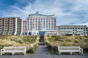 a hotel with two benches in front of a building at Grand Hotel Huis ter Duin in Noordwijk aan Zee