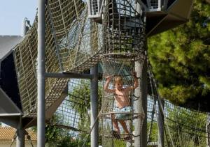 a person is climbing up a tree in a batting cage at Camping Les Sables d'Or Pirates World - Aquatique Vacances in Le Grau-dʼAgde