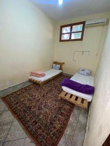 two beds in a room with a rug and a window at GUESTS Of TATA in Tatta