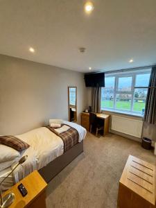 a bedroom with a bed and a desk and a window at King Alfred Hotel in Barrow in Furness