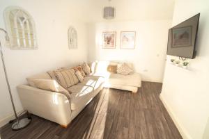 a living room with a couch and a tv at Glenroy House Swansea in Swansea