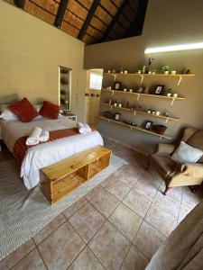 ein Schlafzimmer mit Bett, Bank und Regalen in der Unterkunft Dorpsrus in Bela-Bela + 11 Fotos