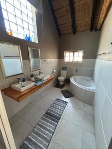 ein Badezimmer mit zwei Waschbecken, einer Badewanne und einer Toilette in der Unterkunft Dorpsrus in Bela-Bela