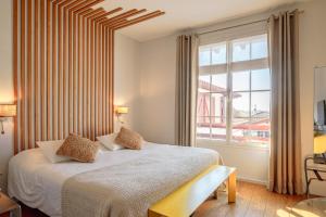 a bedroom with a bed and a large window at Hôtel Briketenia in Guéthary