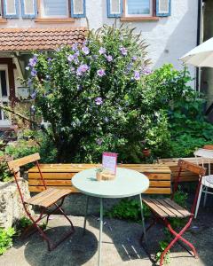a table and two chairs and a bench with purple flowers at Katzenbachlädle in Rottenburg