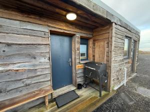 a wooden cabin with a blue door and a grill at Thurso Accommodation in Castletown