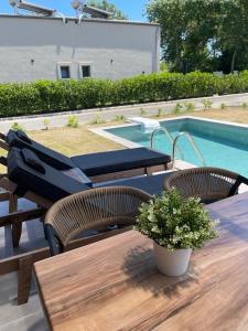 a wooden table with two chairs and a potted plant at Ammos Luxury Pool Villas in Olympic Beach