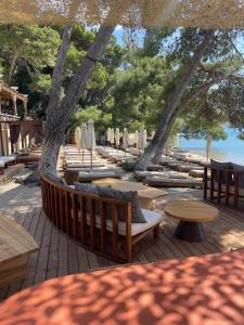 a deck with tables and chairs and tables and trees at Xenia Poros Image Hotel by GHH in Poros