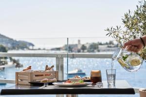 a person pouring a glass of wine on a table at Xenia Poros Image Hotel by GHH in Poros