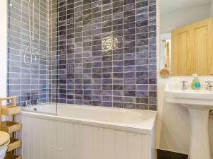 a blue tiled bathroom with a tub and a sink at 1 Bed in Helston oc-82496 in Ruan Minor +12 photos