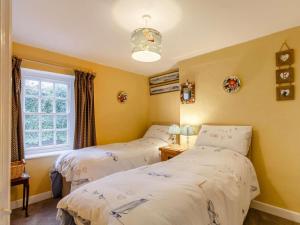 two beds in a room with yellow walls and a window at 2 Bed in Fowey oc-76624 in Fowey