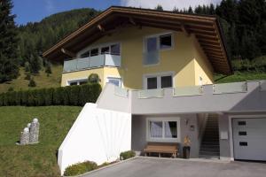 a yellow house with a porch and a driveway at Haus Wibmer in Kals am Großglockner +3 photos