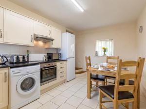 a kitchen with a table and a stove and a dishwasher at 2 Bed in Helston oc-41378 in Cury