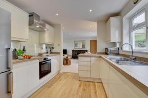 a large kitchen with white cabinets and a sink at 3 Bed in Georgeham oc-halcy in Georgeham