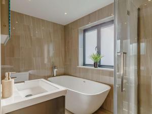 a bathroom with a tub and a sink and a window at 4 Bed in Bude oc-89355 in Poughill +27 photos