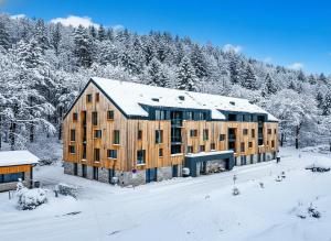 a large wooden building in the snow with trees at Apartmán Mlýn 208 in Vrchlabí