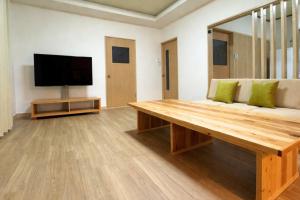 a living room with a wooden bench and a flat screen tv at 白樺 l リノベーション済 l 千歳空港まで30分 l 貸切の一軒家 l 8名様までOK in Yuni