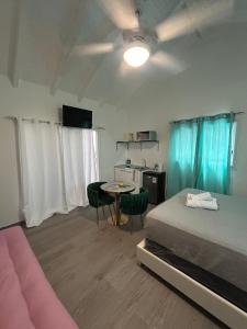 a bedroom with a bed and a table and a kitchen at Blue Sail Rooms in Koolbaai