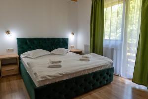a bedroom with a large bed with a green headboard at Villa Panoramic Sovata in Sovata +15 photos