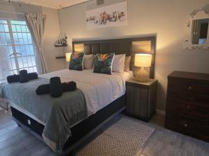 a bedroom with a bed and a dresser with a lamp at Nguni Rest in Barberton