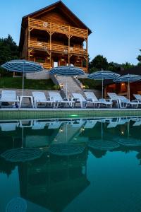 a pool with chairs and umbrellas in front of a building at Villa Panoramic Sovata in Sovata
