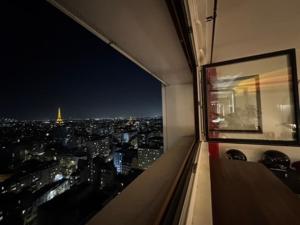 a view of the eiffel tower at night from a window at Eiffel Tower view & Swimming Pool, Cosy appartment - Center in Paris