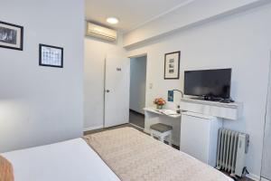 a bedroom with a bed and a desk with a television at La Paz Apart Hotel in Lima
