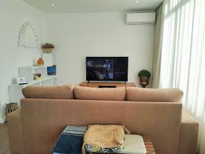a living room with a brown couch and a flat screen tv at Apartamento Mar & Sal in Mindelo +23 photos
