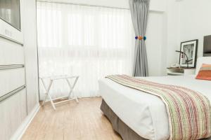 a white bedroom with a bed and a window at La Paz Apart Hotel in Lima
