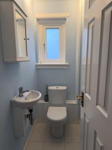 a bathroom with a toilet and a sink and a window at Spacious Glasgow Group Stay in Glasgow