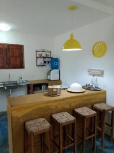a kitchen with a counter and stools in a room at Casa Bosque Guajiru in Trairi