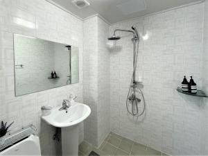 a white bathroom with a sink and a shower at HY Choi Hostel in Seogwipo +76 photos