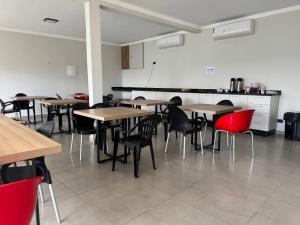 a room with tables and chairs and a kitchen at Hotel dallas in Telêmaco Borba