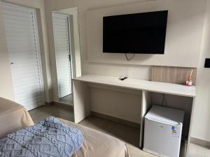 a room with a desk with a television on a wall at Hotel dallas in Telêmaco Borba