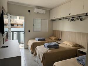 a bedroom with two beds and a balcony at Hotel dallas in Telêmaco Borba
