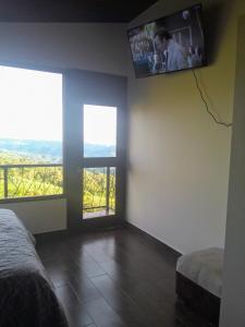 a bedroom with a tv on the wall and two windows at Suite relax entre naturaleza y piscina en Tulipe in El Porvenir