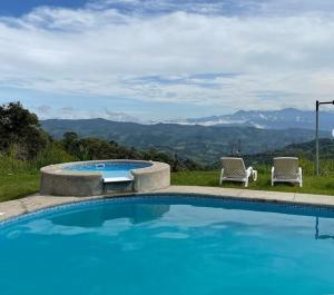 a swimming pool with two chairs and a view of mountains at Suite relax entre naturaleza y piscina en Tulipe in El Porvenir