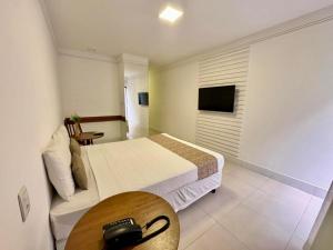 a room with a bed and a table and a television at Recanto da Passagem Premium Hotel in Cabo Frio