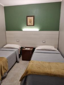 two beds in a room with a green wall at La Casa del Viajero in Presidencia Roque Sáenz Peña