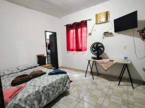 a bedroom with two beds and a table and a television at Casa em Mosqueiro com Piscina in Belém