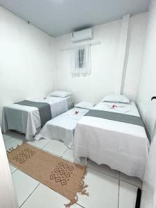 a room with two beds and a rug on the floor at Ksa Sodré in Barreirinhas