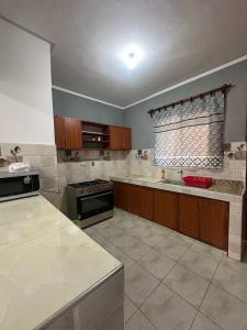 a large kitchen with white counter tops and a window at Diddy & Eddy's apartment in Malindi