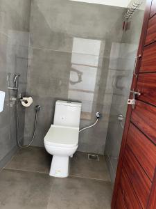 a bathroom with a white toilet and a shower at Murthy Surf School in Covelong