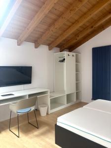 a bedroom with a desk with a tv and a chair at D&D Guesthouse in Angelbachtal